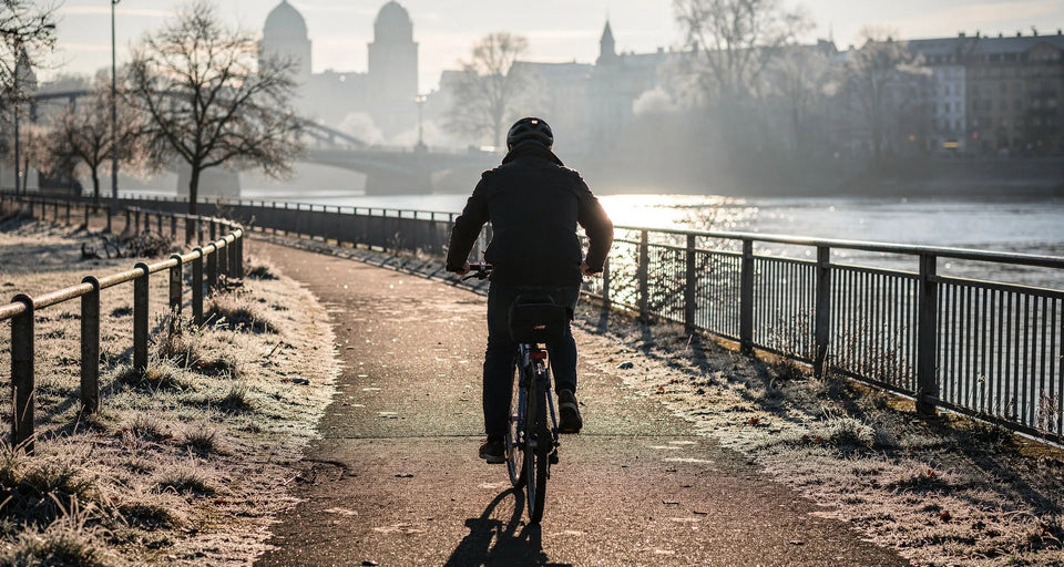 Radfahrer auf einem frostigen Uferweg in der Stadt im Wintermorgenlicht