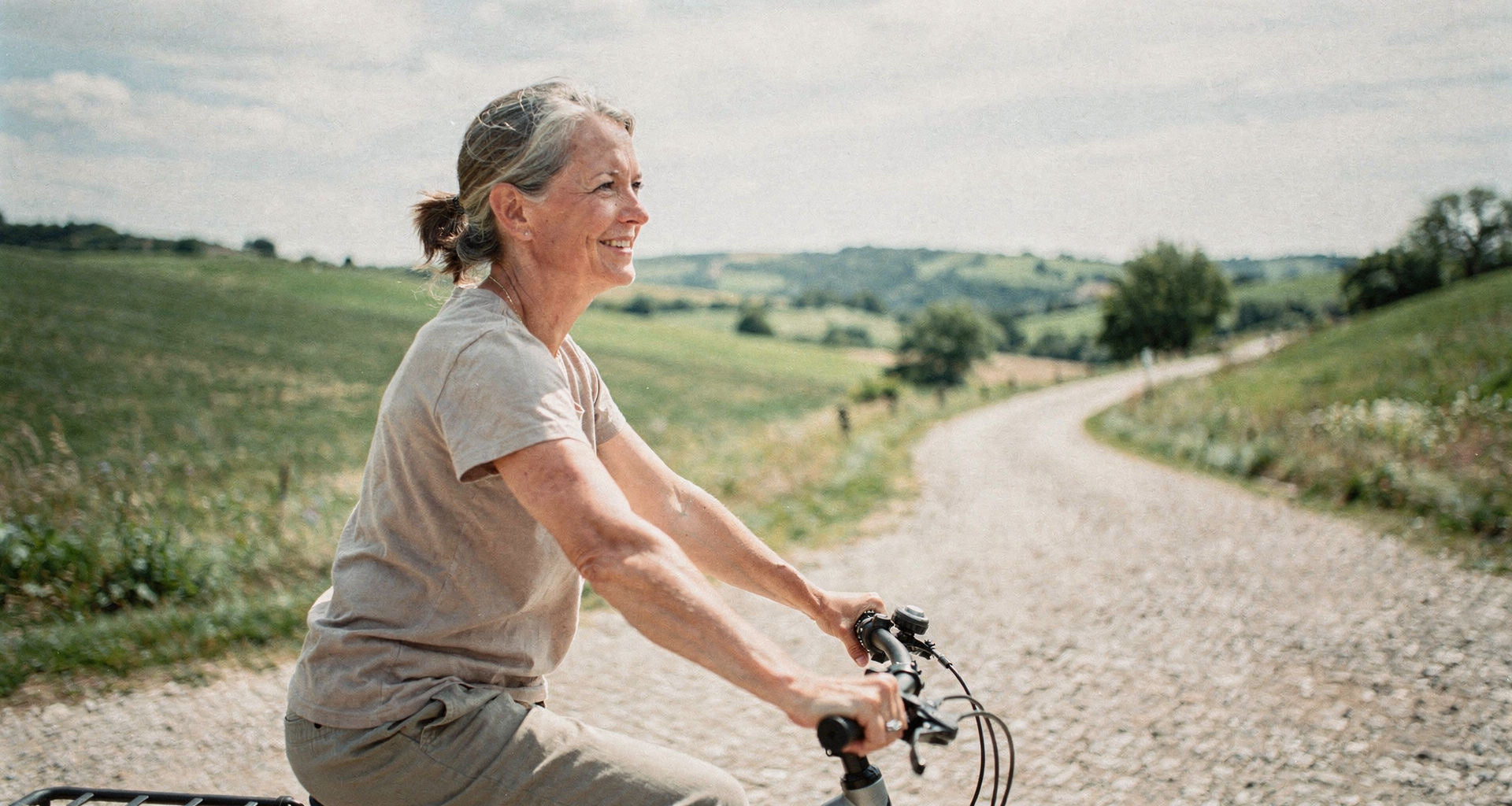 Entspannt aufrecht sitzende Radfahrerin auf einem Trekking-E-Bike auf einem Schotterweg